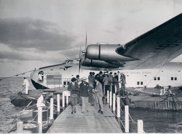 1940 customers deplane in Lisbon fromBoeing B314 American Clipper, registration NC18606 while ground crew unload customer luggage from the bow hatch.